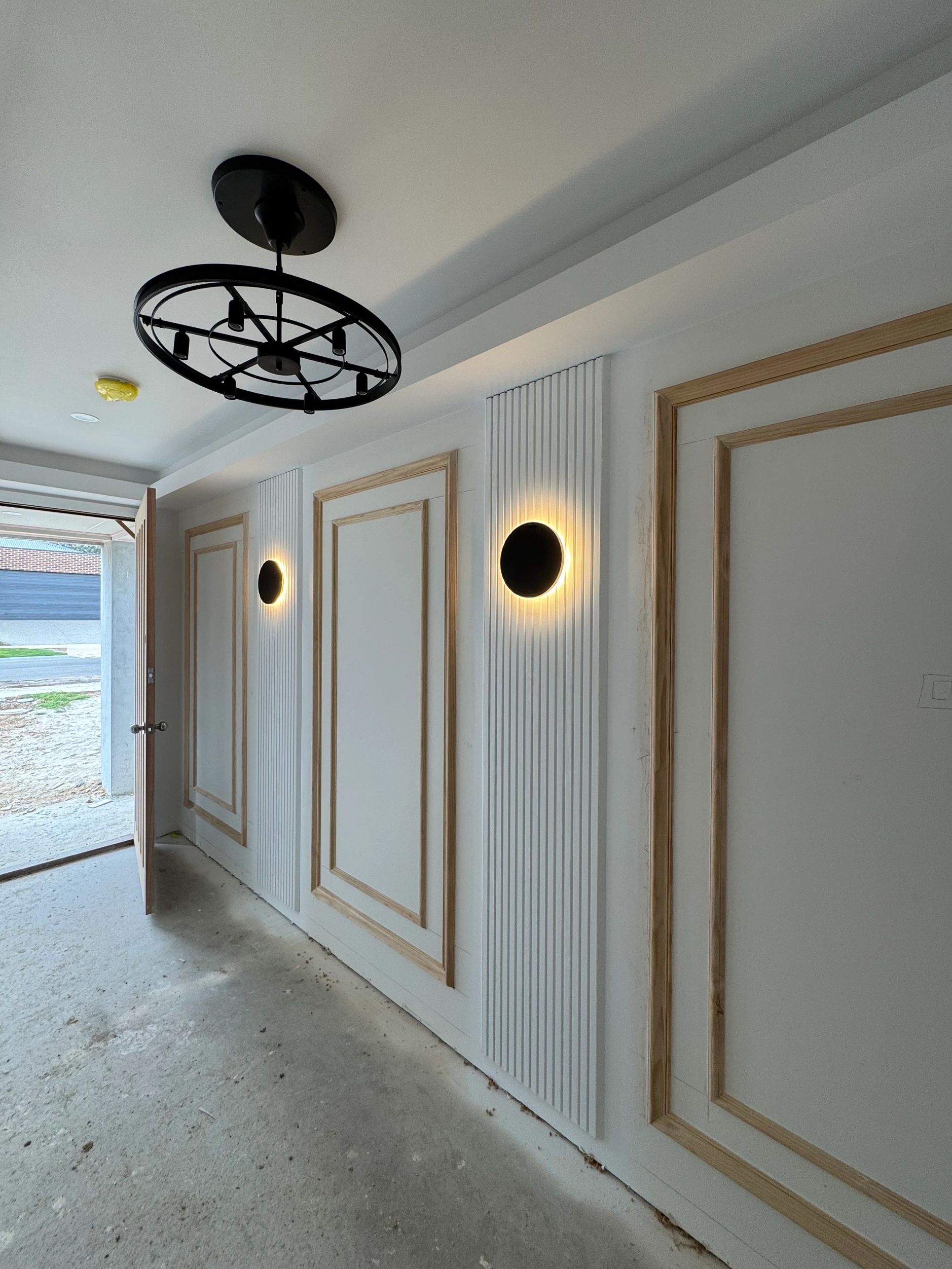 Corridor with wall sconces and geometric ceiling fan