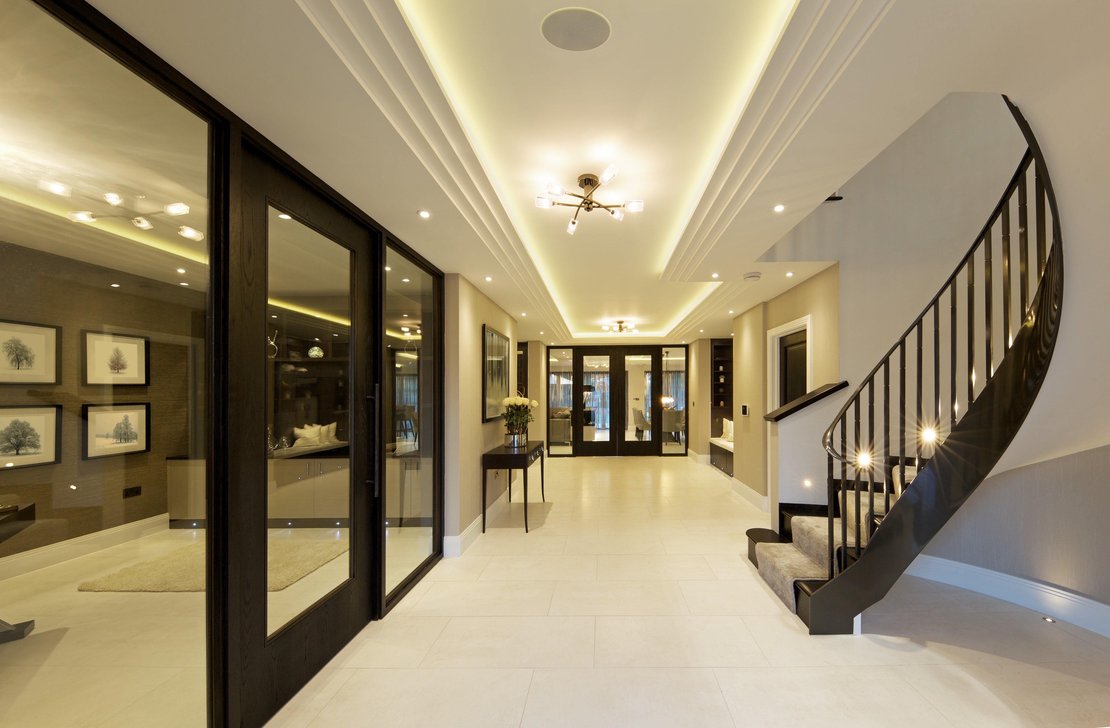 Grand residential hallway with cove lighting, recessed downlights, and elegant architectural finishes
